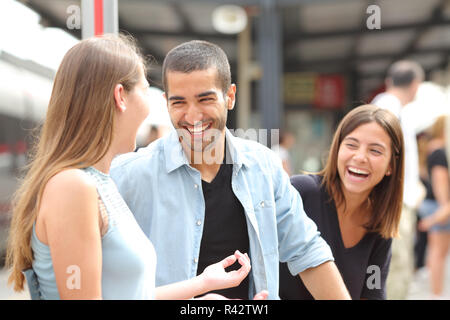 Tre amici a parlare e ridere in una stazione ferroviaria Foto Stock