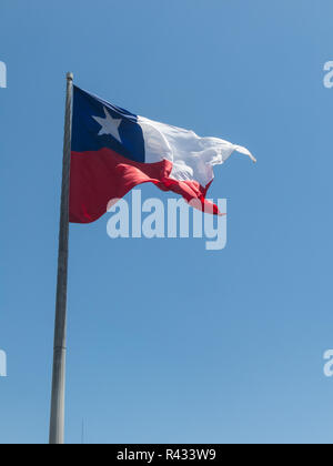 Bandiera del Cile vola in un vento forte contro un luminoso cielo blu con i riflessi del sole. Simbolo patriottico del Cile, America del Sud. Foto Stock