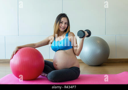 Ritratto di asian femmine gravide di fare esercizio nella sala sportiva, sollevamento pesi, sana maternità concept Foto Stock