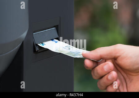 Persona della mano inserire nota di valuta nel parcheggio macchina Foto Stock