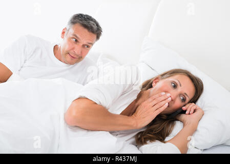 Uomo che guarda la donna parlando al telefono cellulare Foto Stock