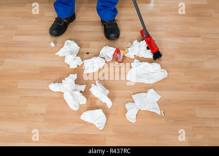 Bidello di spazzamento carta accartocciata sul pavimento Foto Stock