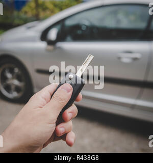 L uomo si apre la sua auto porta con il telecomando di controllo chiave. Maschio presse a mano sul veicolo di controllo remoto del sistema di allarme su auto parcheggiata sullo sfondo. Spegnimento Foto Stock