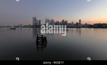 La mattina presto sul lato della Groenlandia accanto alla Marina Sud Dock con una bella vista al Canary Wharf area. Riverside acqua tranquilla con bella riflessioni. Foto Stock