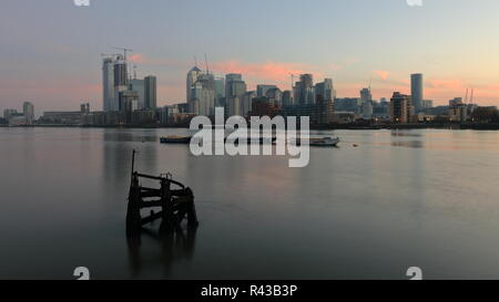 La mattina presto sul lato della Groenlandia accanto alla Marina Sud Dock con una bella vista al Canary Wharf area. Riverside acqua tranquilla con bella riflessioni. Foto Stock