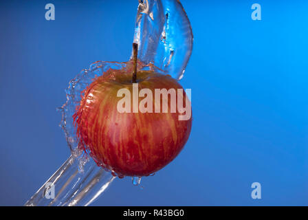 Organici mela rossa acqua splash sfondo blu Foto Stock