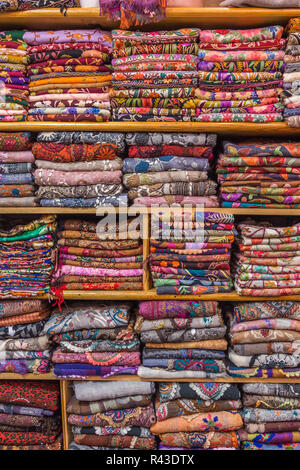 Foulard colorati visualizzati ordinatamente ripiegati sui ripiani, pronti per la vendita in un bazar. Foto Stock