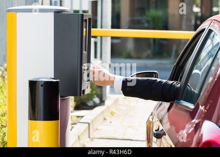 L'uomo inserimento di biglietto per area di parcheggio Foto Stock