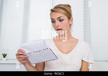 Scioccato donna lettura la Lettera a casa Foto Stock