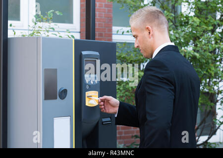 L'uomo inserimento di biglietto per pagare per il parcheggio Foto Stock