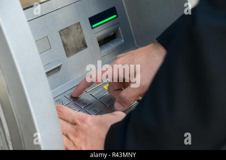 Mano utilizzando tastiera macchina ATM Foto Stock