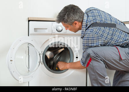 Repairman controllo macchina di lavaggio a casa Foto Stock