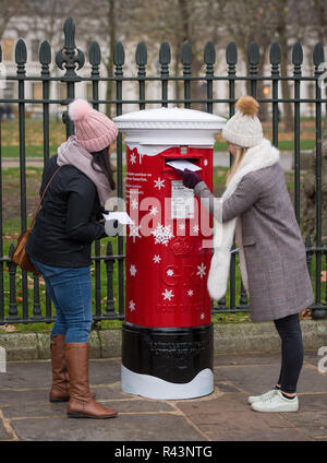 È sotto embargo per 0001 Lunedì 26 Novembre Gabriella Bowen (sinistra) e Jasmin Prichard cartoline in uno dei Royal Mail il primo "Singing postboxes', in Greenwich, London, che riproduce una di una selezione di tre a tema natalizio canzoni quando una lettera o una scheda è pubblicato. Foto Stock