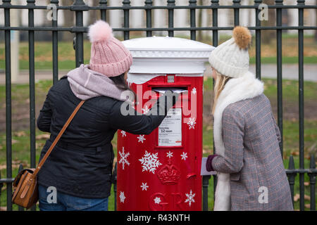 È sotto embargo per 0001 Lunedì 26 Novembre Gabriella Bowen (sinistra) e Jasmin Prichard cartoline in uno dei Royal Mail il primo "Singing postboxes', in Greenwich, London, che riproduce una di una selezione di tre a tema natalizio canzoni quando una lettera o una scheda è pubblicato. Foto Stock