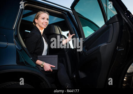 Sorridente imprenditrice uscendo da auto Foto Stock