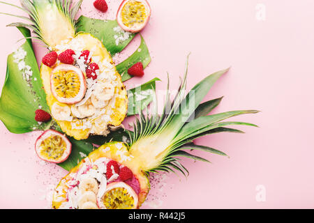 Gustoso frullato di appetitosi bocce servita in metà ananas decorato con taglio frutto della passione, scaglie di noce di cocco e semi di chia.la vita sana pulire mangiare co Foto Stock