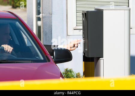 L'uomo inserimento di biglietto per area di parcheggio Foto Stock