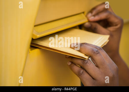 Persona della mano inserire la lettera nella cassetta postale Foto Stock