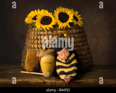 Carino baby in bee outfit dormire contro l'alveare di antiquariato Foto Stock