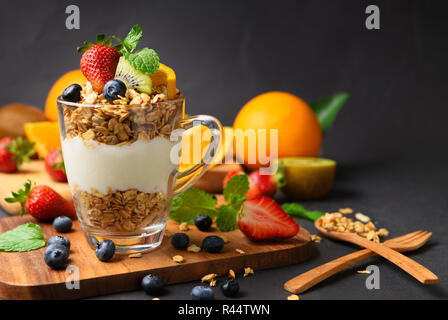 Cereali e yogurt e frutta su topping in vetro sulla tavola di legno, cibo sano per il concetto di dieta Foto Stock