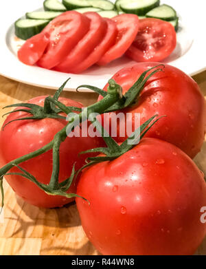 Un angolo foto di tre pomodori rossi unite da un gambo verde in primo piano Foto Stock