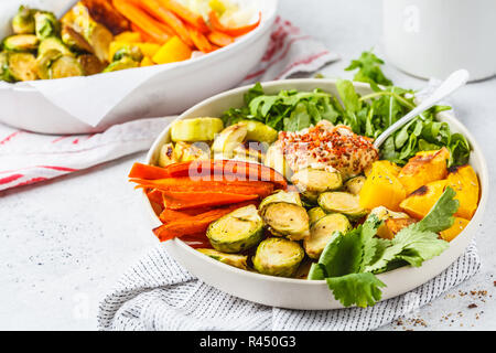 Verdure cotte e hummus insalata in un piatto bianco. Sano cibo vegan concetto. Foto Stock