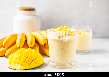 Mango frullato di banana con noce di cocco in un vaso. Impianto basato il concetto di cibo. Foto Stock