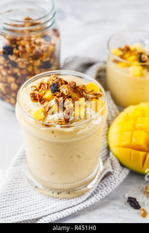 Frullato di mango con granola e noce di cocco in un vaso. Sano cibo vegan concetto. Foto Stock