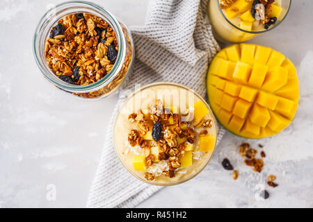 Frullato di mango con granola e noce di cocco in un vaso. Sano cibo vegan concetto. Foto Stock
