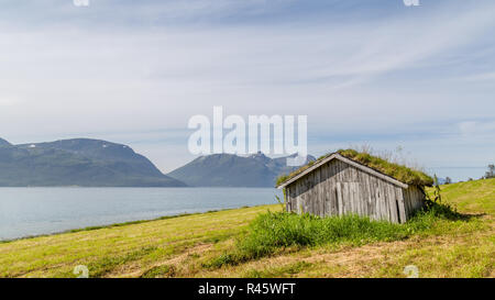 Tipico paesaggio scandinavo con una vecchia capanna con un tetto verde lungo un lago Foto Stock