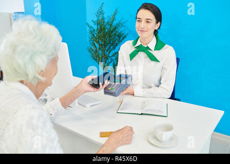 Contenuto banca rappresentante del cliente aiutando senior client a noi Foto Stock