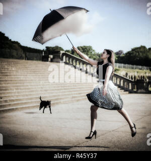 La donna il salto e la cattura di Cloud con ombrellone Foto Stock