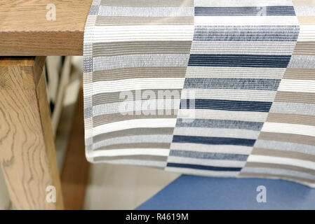 Svuotare tavolo in legno rivestito con una biancheria striped panno da cucina e la sfondo sfocato, bokeh di fondo. Foto Stock