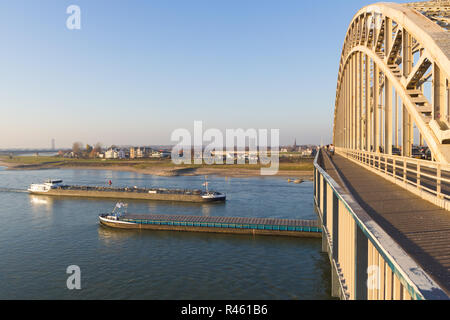 Nijmegen, Paesi Bassi - 16 Novembre 2018: cargo chiatte sul fiume passando sotto il ponte waal a Nijmegen durante il tempo di bassi livelli di fiume Foto Stock