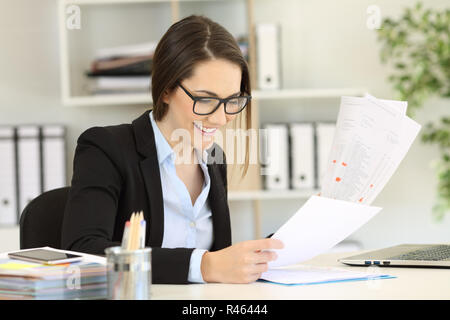 Felice lavoratore di ufficio indossando occhiali confrontando i documenti su carta Foto Stock