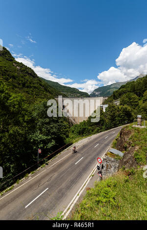 Ciclista su strada nei pressi di Verzasca Contra Dam e Mergoscia village sopra. Distretto Di Locarno, Tichino, Svizzera Foto Stock