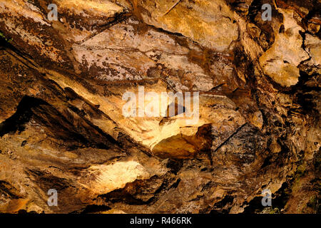 Parete naturale di roccia marrone sulla luce del tramonto. Foto Stock