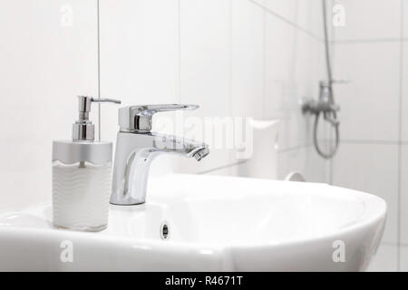 Dissipatore di bianco con rubinetto di acciaio in un bagno Foto Stock