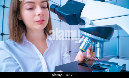 Scienziato analizzando vetrino del microscopio in laboratorio. Giovane donna tecnico sta esaminando un campione istologico, una biopsia in laboratorio di cancro ri Foto Stock