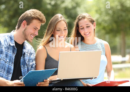 Tre Allievi felici e-learning insieme seduta su una panchina in un campus Foto Stock