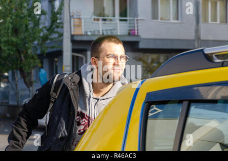 Un bel giovane uomo salire in un taxi .Egli è triste. Foto Stock