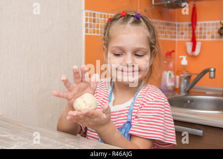 Felice bambina ragazza scolpisce una torta al tavolo della cucina Foto Stock