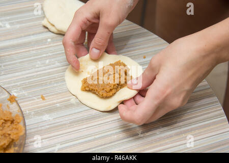 Sulla torta degli appalti impasto è il riempimento, donna cieca&#39 s mani la preparazione di pasticceria Foto Stock