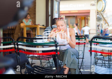 Donna di mangiare pizza outdoor in caffetteria. Foto Stock