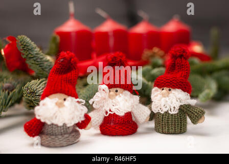 Tre piccoli nani di Natale di fronte quattro candele e verde rami di abete Foto Stock