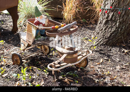 Gnomo da giardino in sella a una delle quattro ruote vecchio arrugginito biciclette per bambini Foto Stock