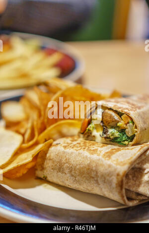 Close up veggie wrap e handmade potato chips su piastra in ristorante Foto Stock