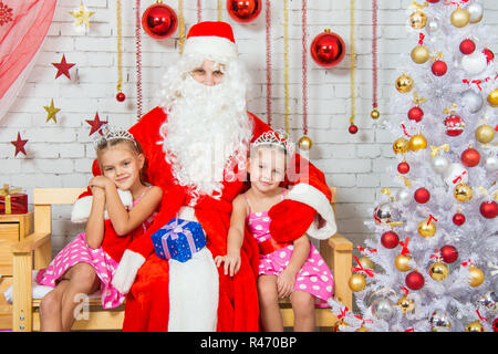 Babbo Natale che abbraccia due ragazze sorelle Foto Stock