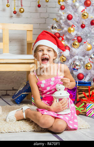 Ragazza grida felicemente tenendo la candela in mano e seduta da alberi di Natale Foto Stock