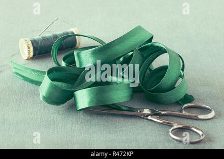 In raso verde il legame di polarizzazione close up con forbici e filo Foto Stock